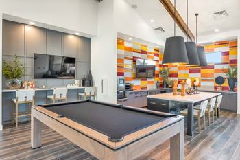 A game room with a pool table and a kitchen with a tv